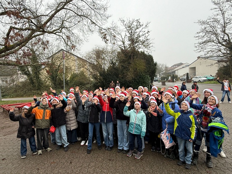 Gruppe winkender Kinder mit Nikolausmützen im Schulhof
